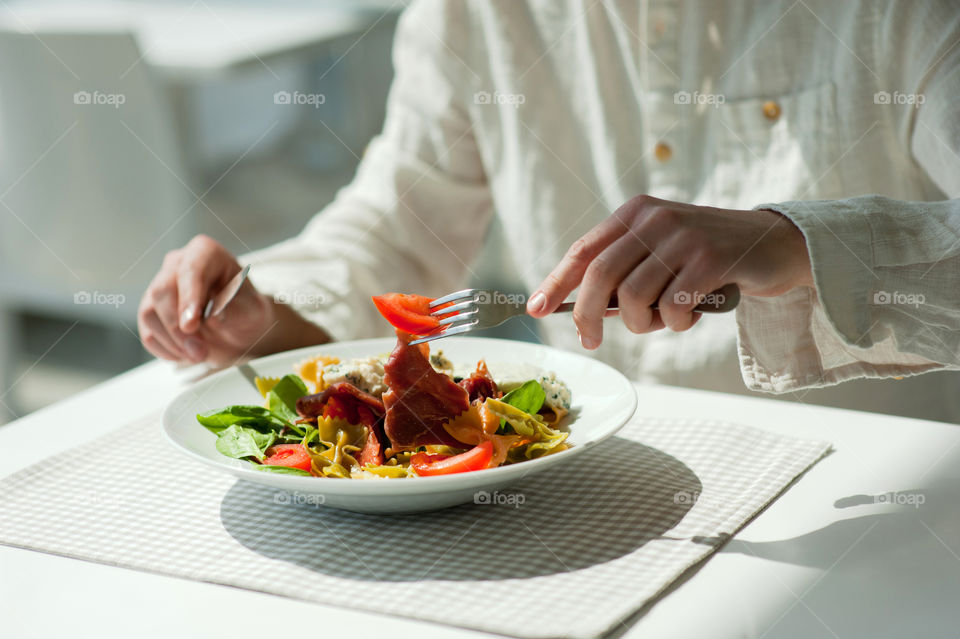 close-up of a young man eating a salad in a light kitchen