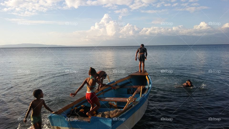 Niños Saltando de una canoa en la playa