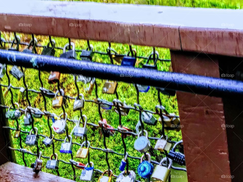 love locks and wish locks attached to metal railing off bridge