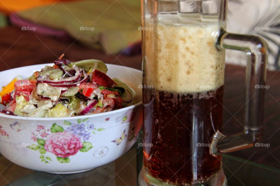 Close-up of a bowl of salad and a glass of dark beer