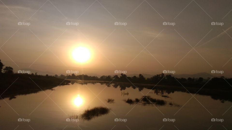 Illuminating sunrays shattered with crimson hues on wide spread horizon.