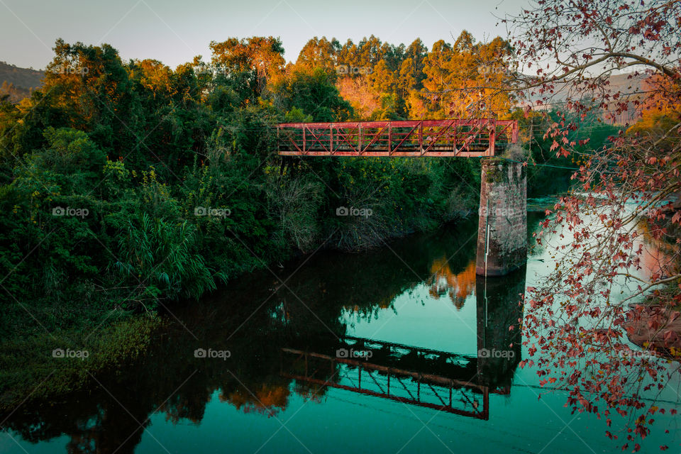 An old bridge reflected in calm river water in autumn.
