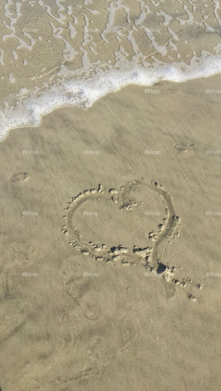 Love at the beach . A heart drawn in the sand 