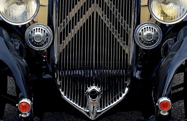The front of a black, cream and burgundy Citroën Rosalie showing the grill and front lights at Cherbourg car show