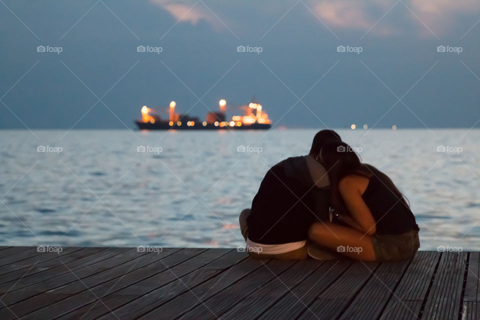 Romantic young couple sitting on pier