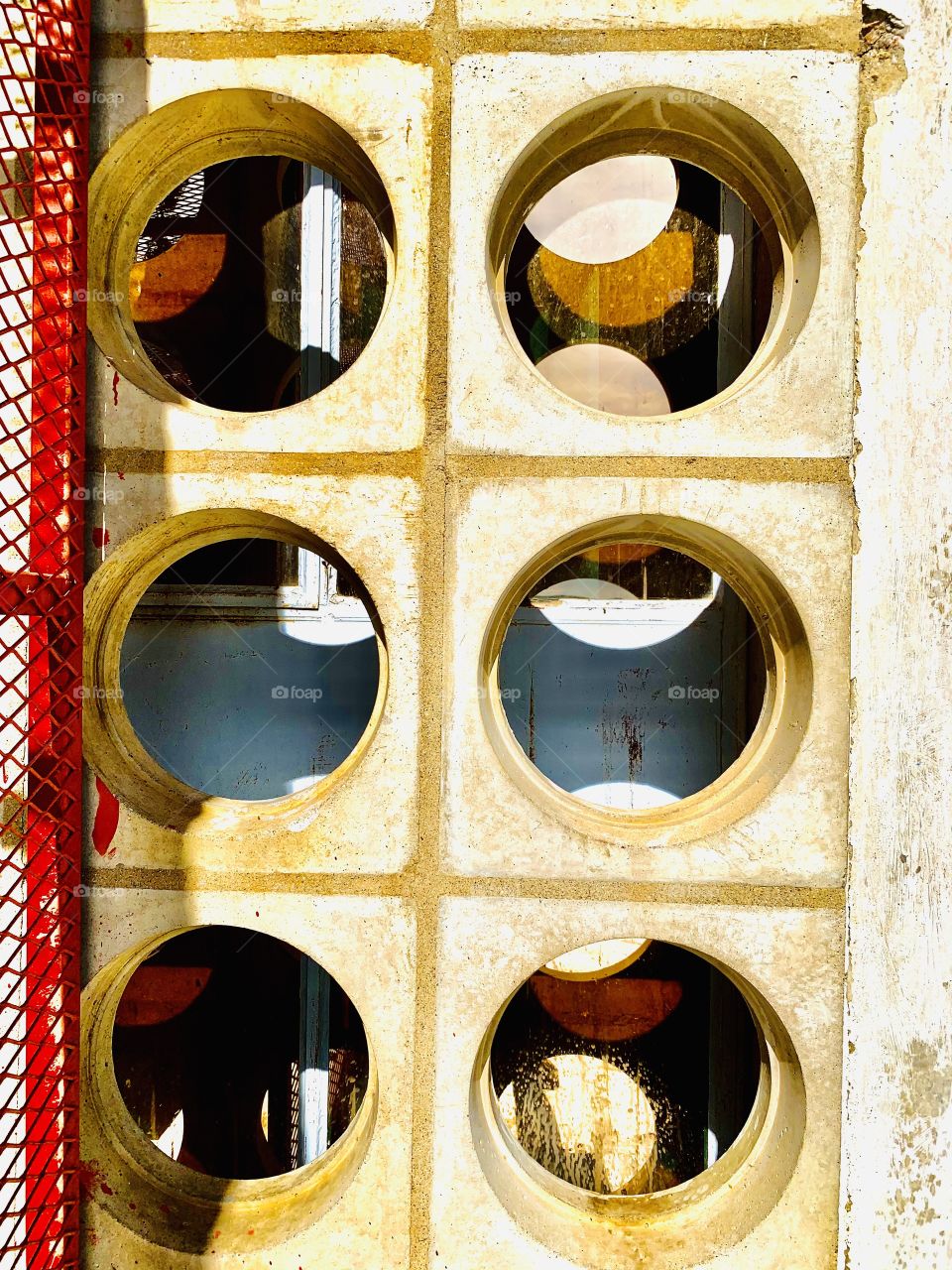 Circular holes in the wall, with transparent glass partition in the background. The wall of the hospital has been standing for ages. That is why spider webs are seen in the dents.