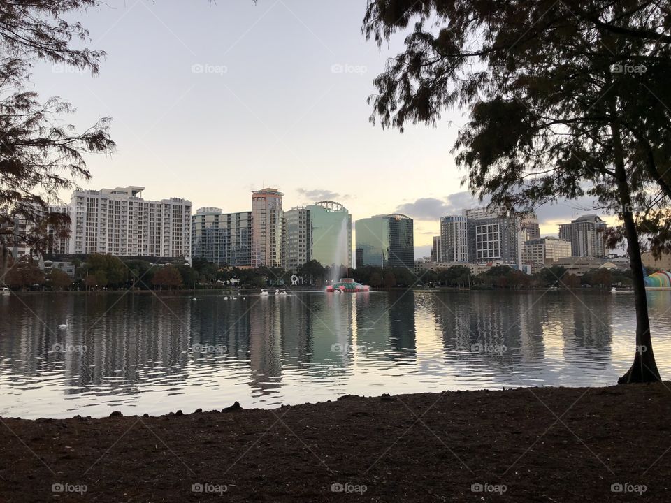 City scape of Orlando as it reflects on Lake Eola while the sun is beginning to set over the city