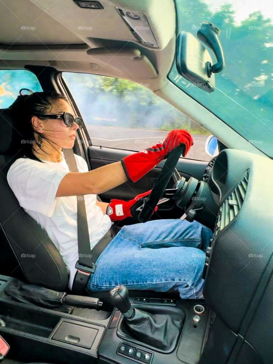 Portrait of a young woman driving a car wearing red gloves