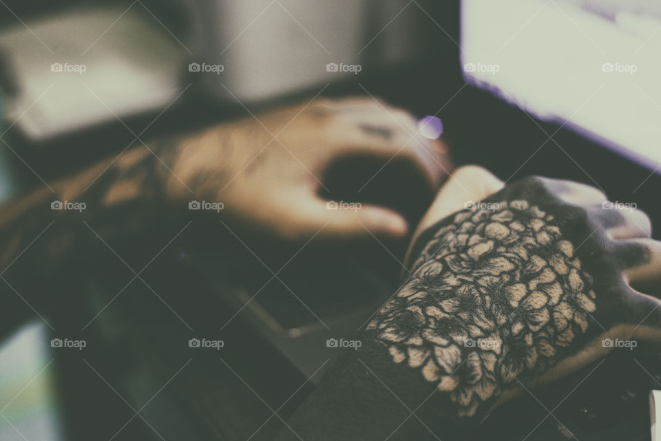 close up of inked hand tattoed working on a compter keyboard