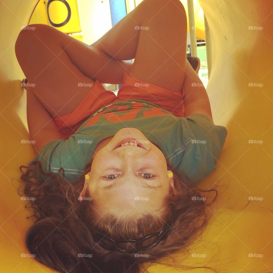 Young girl lying in crawl tube at playground and smiling