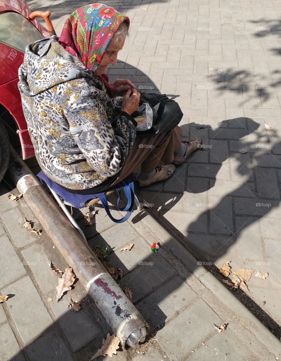 This woman is poor. She got tired and seat down to get something to eat. As you can see she has just bread.