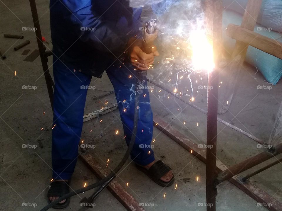 In this remarkable photo, my father is captured working diligently and with unwavering dedication in the welding process. The flying sparks add a dynamic and vibrant touch to the scene, showcasing his high skill and masterful craftsmanship.