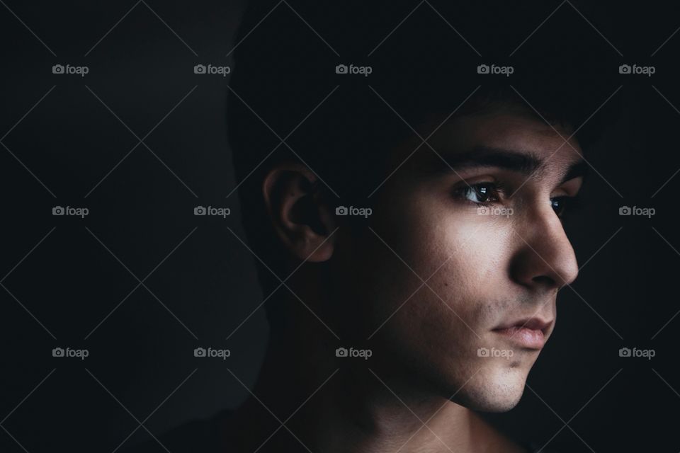 Young man in a dark room with harsh lighting