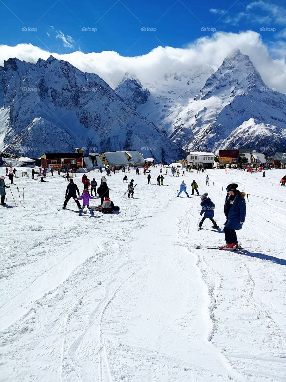 Winter.  December.  Snow.  Time to take care of your health.  Snowy mountains.  The clouds "lie" on the top of the mountains.  Adults and children go skiing