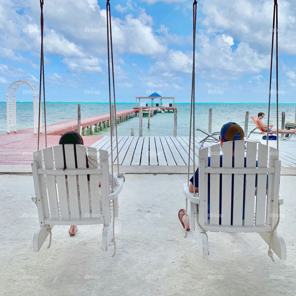 Two friends sitting in white chairs in the warm sun overlooking crystal blue waters in the Caribbean