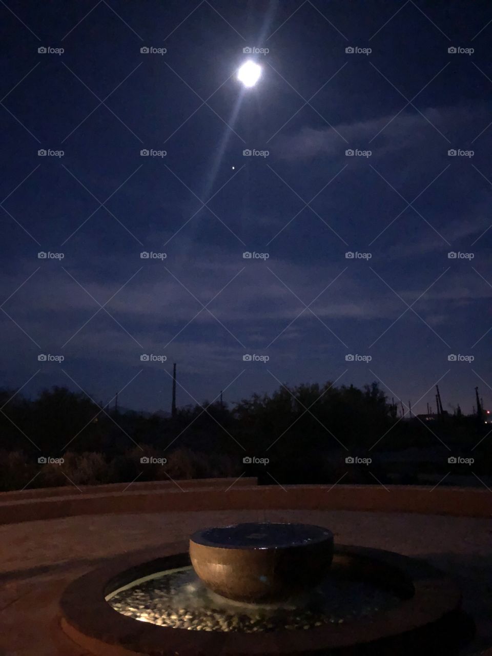 A stunning moonlit evening in Tucson, Arizona featuring a fountain and some evening stars. 