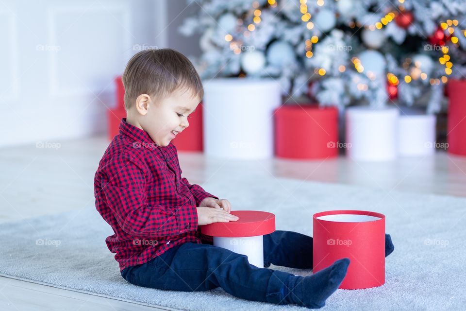 boy and gift box next to christmas tree