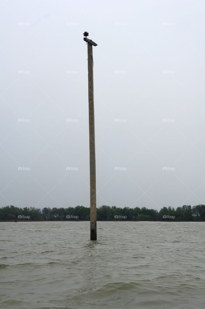 The electricity pole is located in the water.
