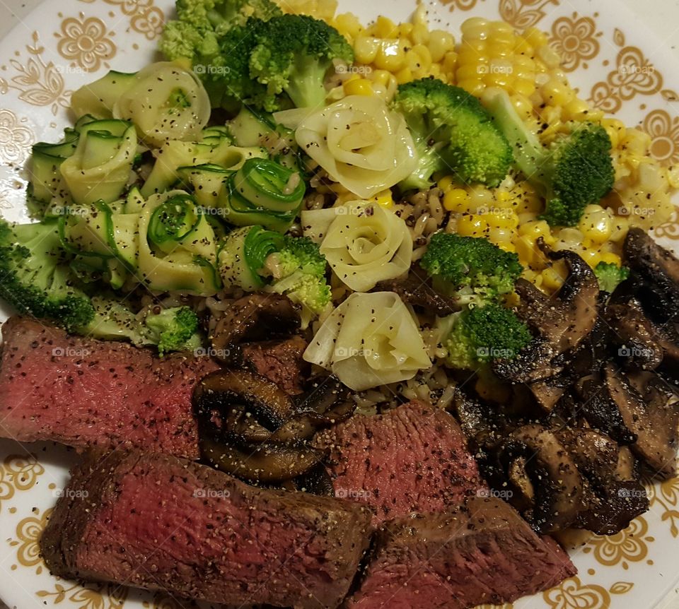 Steak with mushrooms, broccoli, corn, zucchini, and white carrots over quinoa.