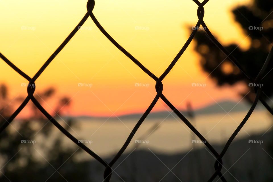 Metal fence close up and sunset background