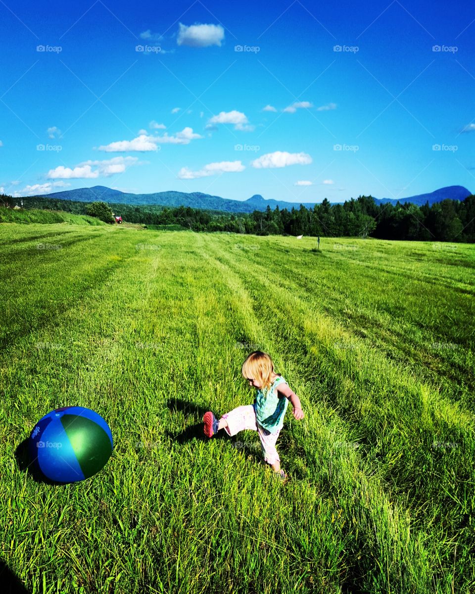 Little girl playing with ball on field
