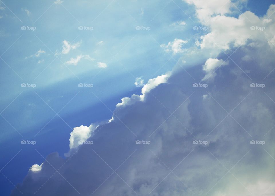 Rays of sunlight  streaming from behind silvery blue clouds