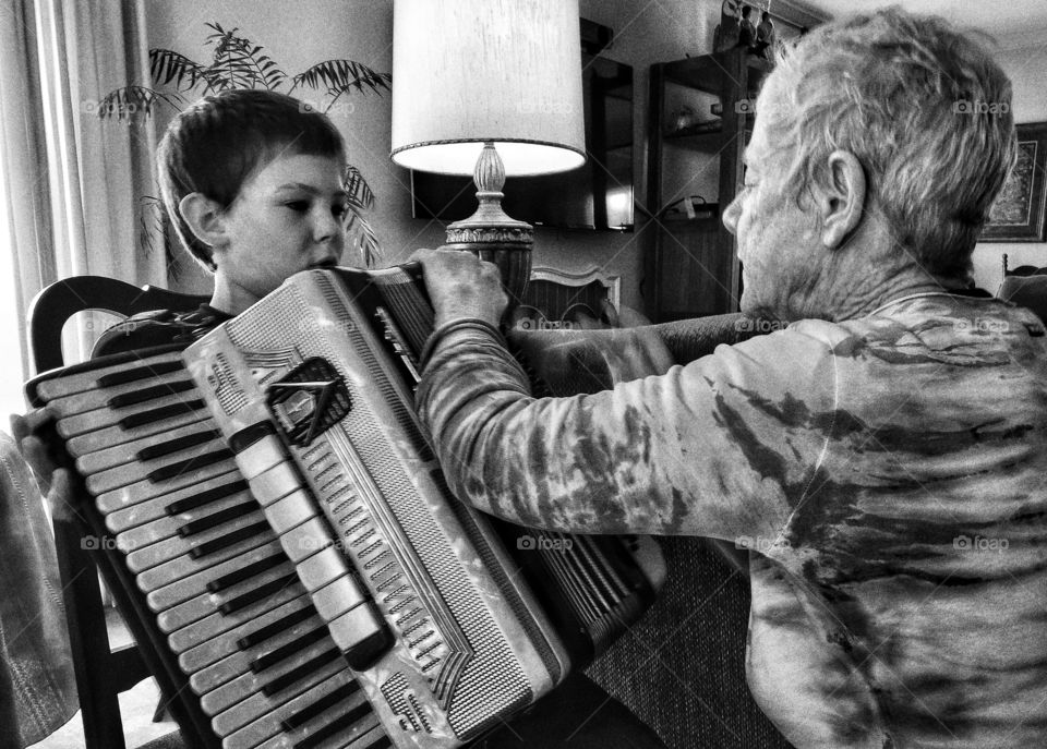 Boy Playing Accordion. Grandmother teaching boy to play accordion