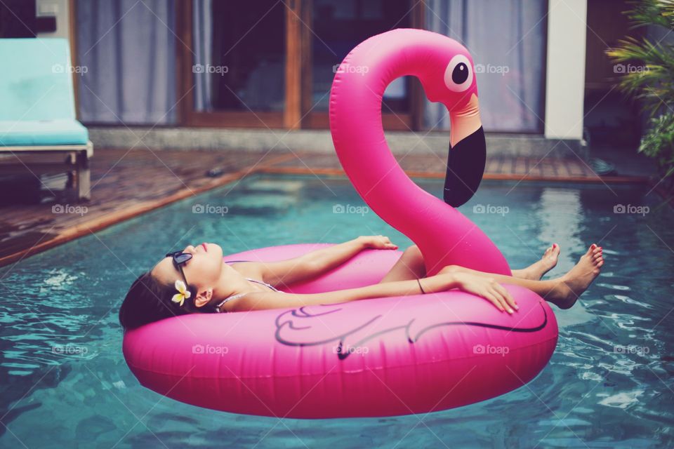 Girl in the pool on a pink flamingo floaty 