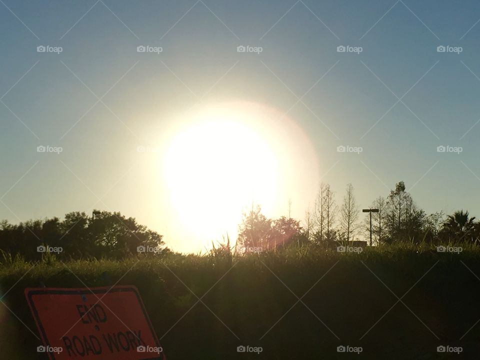 Giant Sunset over trees, grass and end construction sign in Florida 