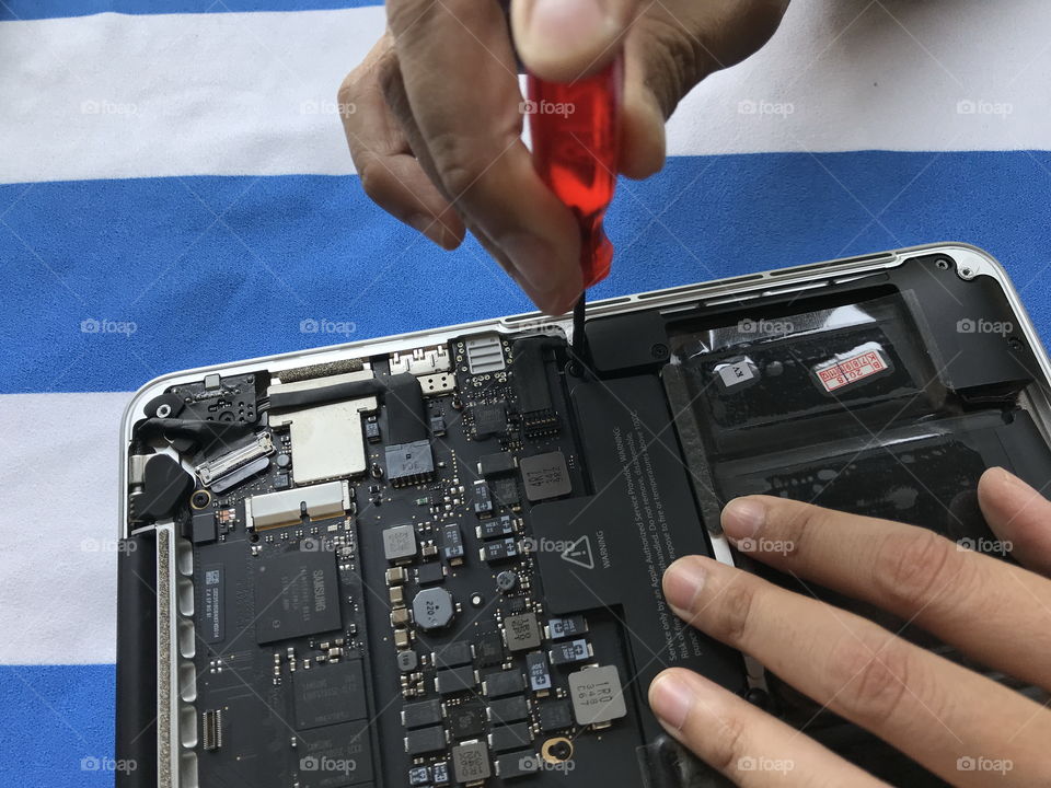 Phuket, Thailand – March 15, 2019: user of Apple Mac book laptop is showing how to change battery by herself at home