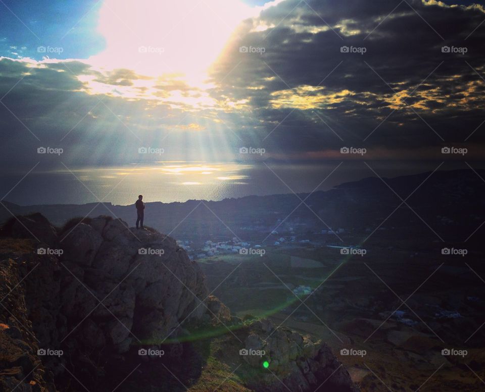 Silhouette of person standing on rock during sunset