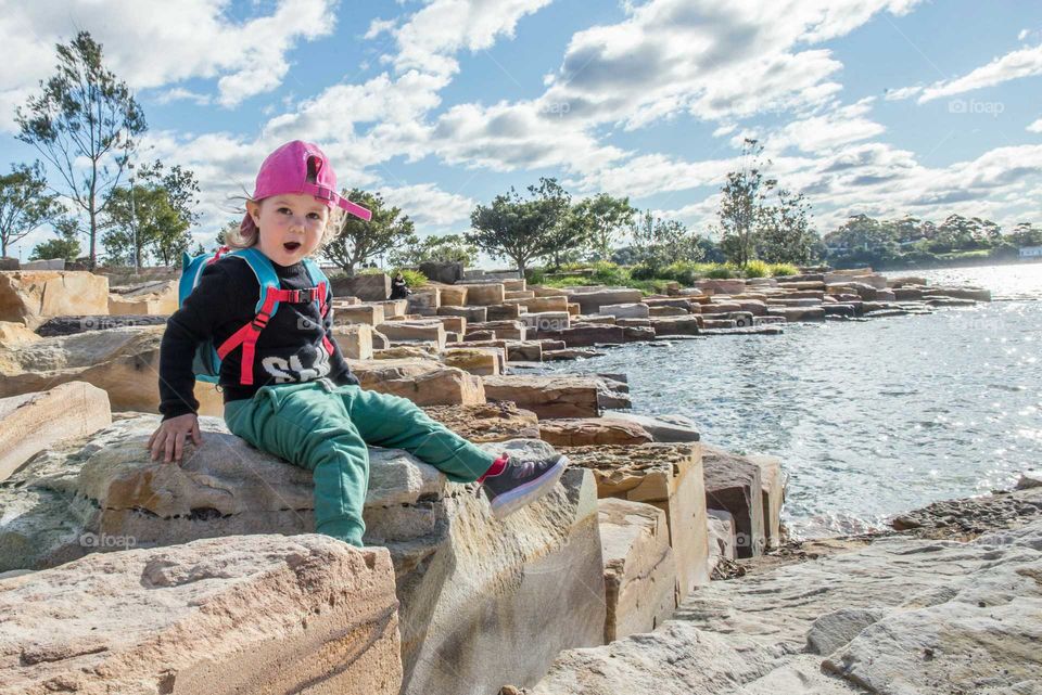 Boy sitting on rock near sea side