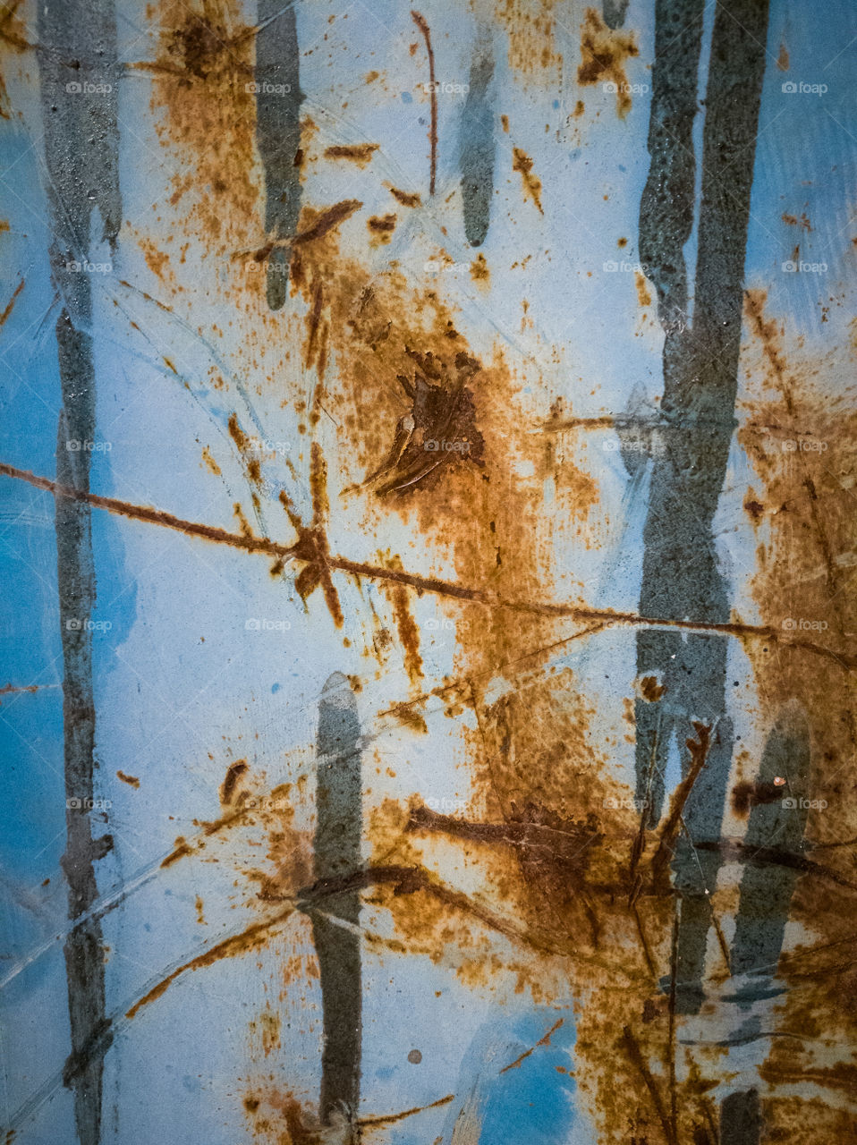 old rusty metal surface creates some abstract textures on a light blue background
