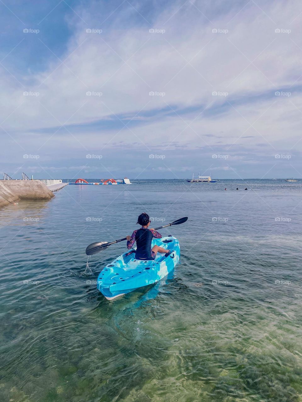A woman enjoys quality time in her kayak. Calm tropical beach at Mactan Cebu Philippines. 
