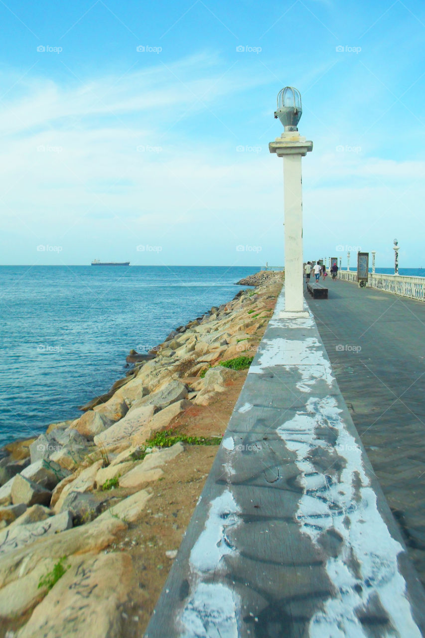 Pier on the beach with ship on the horizon