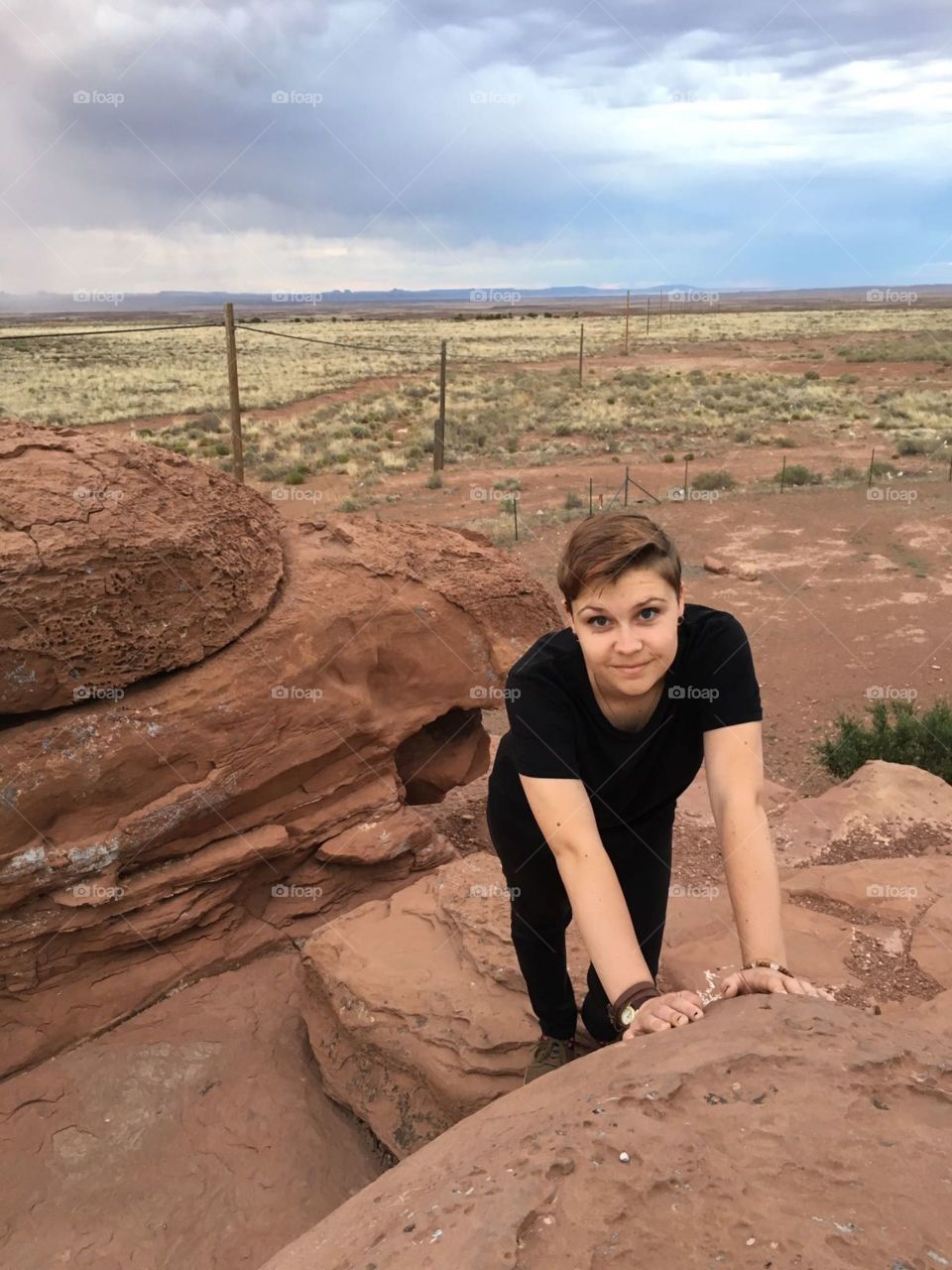 Girl Smiling and Leaning Forward Against Desert Rock
