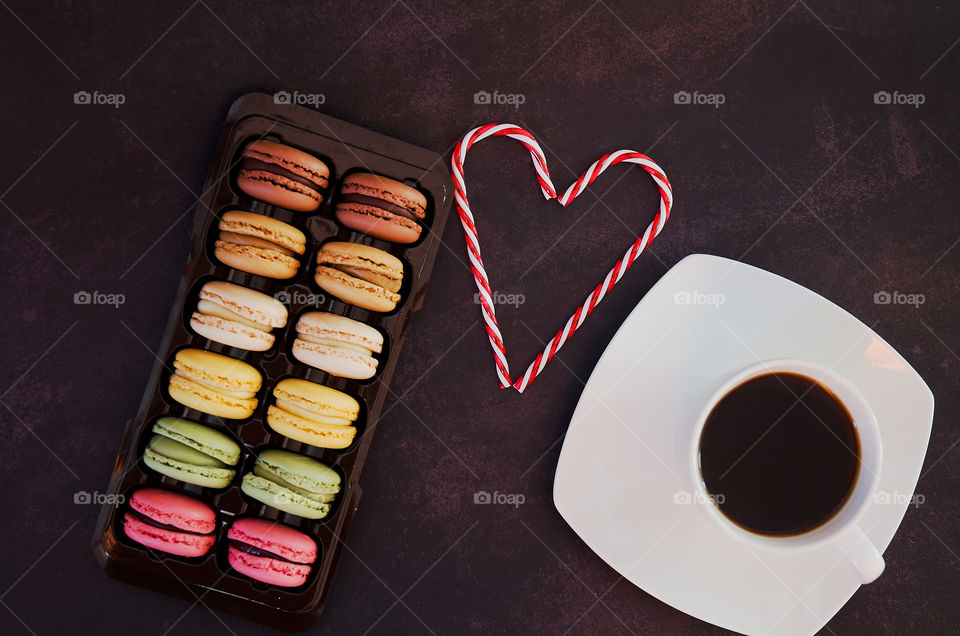 Background of the colorful delicious macaroons at dark table close up. Valentine's day. Greetings card. Flat lay.