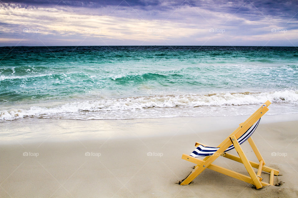lone deck chair on an empty beach by the ocean