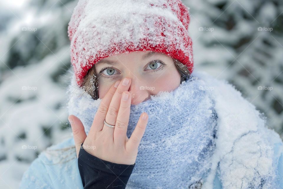 A girl on a walk, beautiful winter with snow, snow on her hat and face.

￼