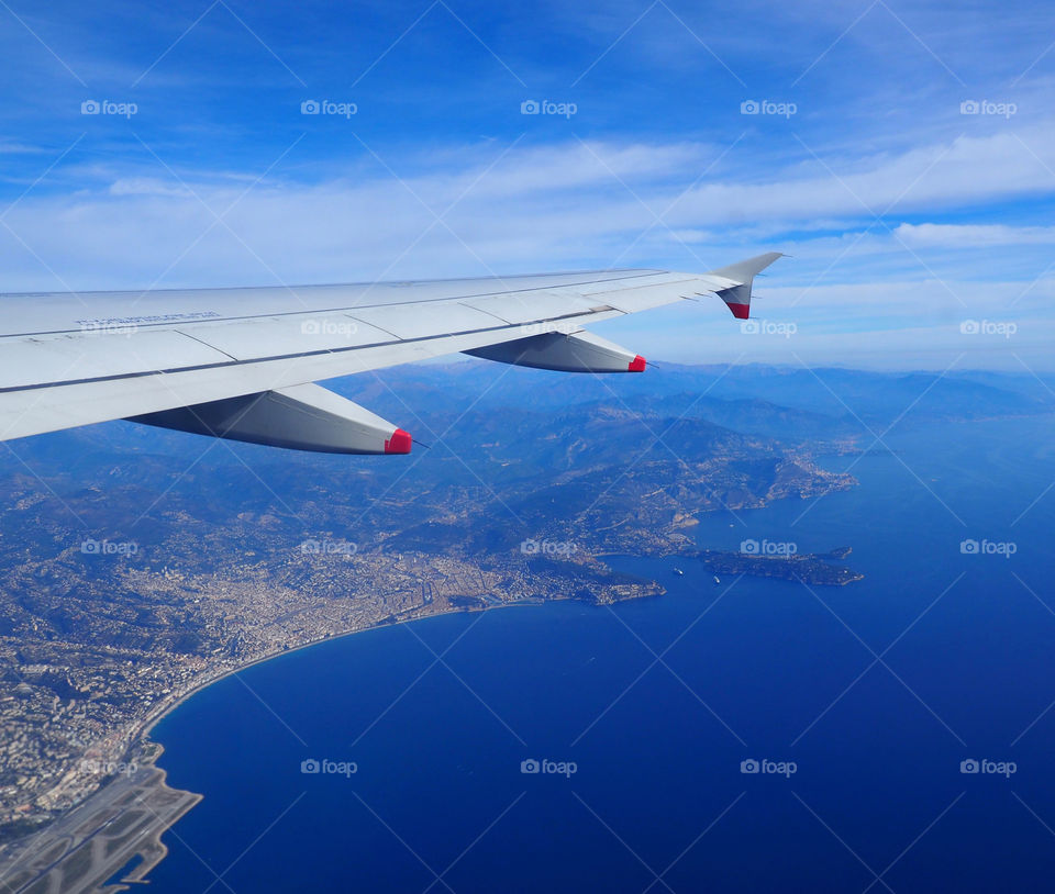 View of the French Riviera from behind wing on airplane flying over Nice, France.