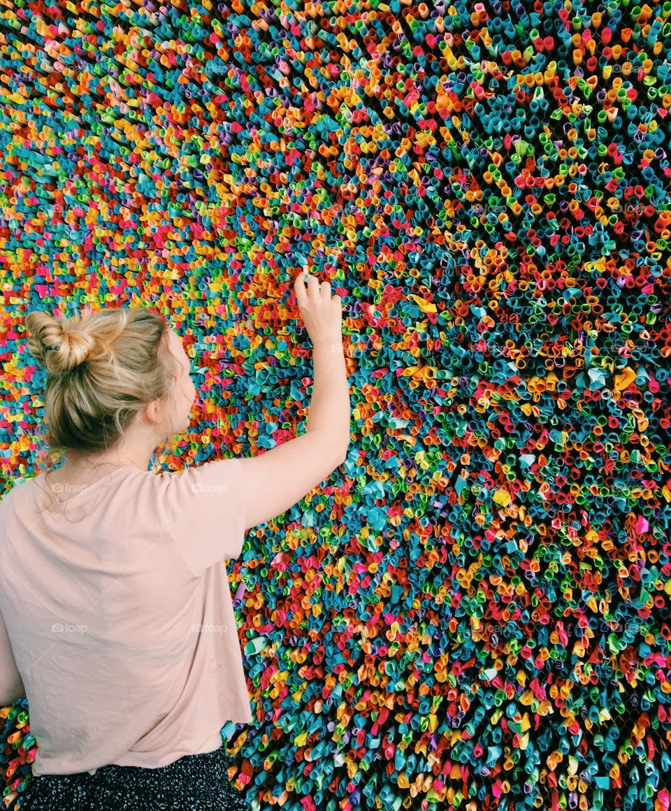 Girl in front of colorful paper wall.