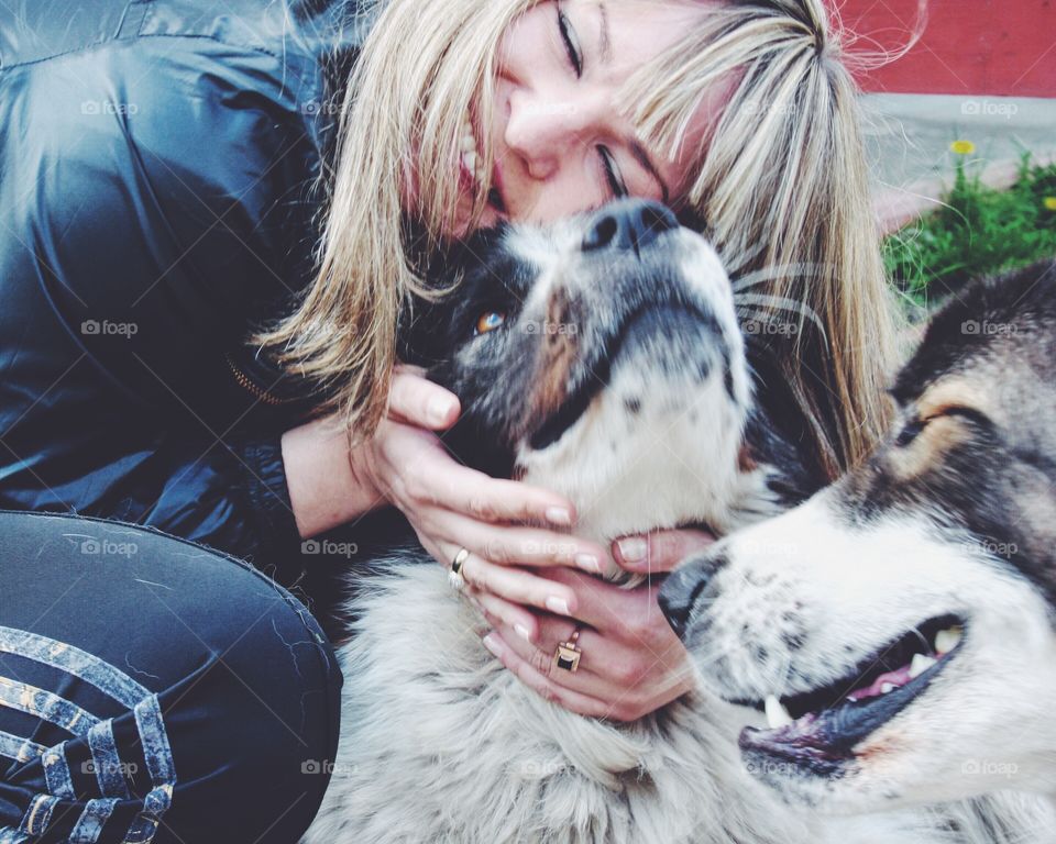 Long haired blonde girl hugging smiling dogs 