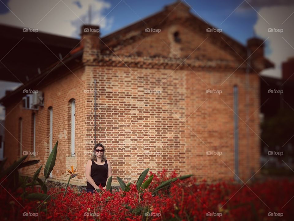 Lovely lady in a garden full of red flowers, and vintage buildings. Romance may be in the air...