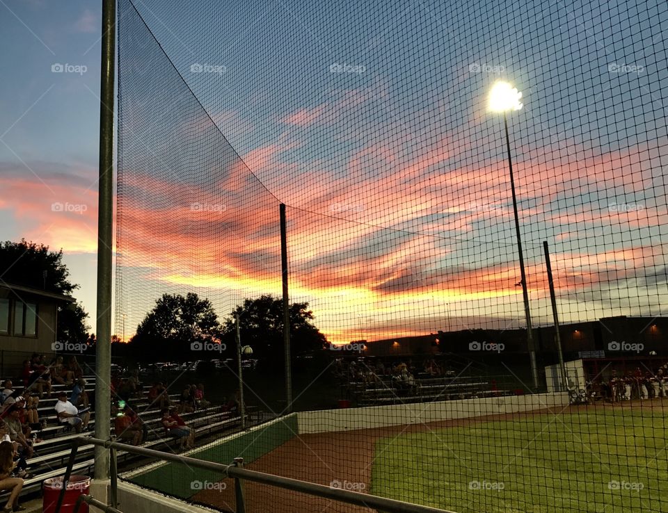 Colorful and beautiful sunset behind a high school baseball field on a hot summer evening. 