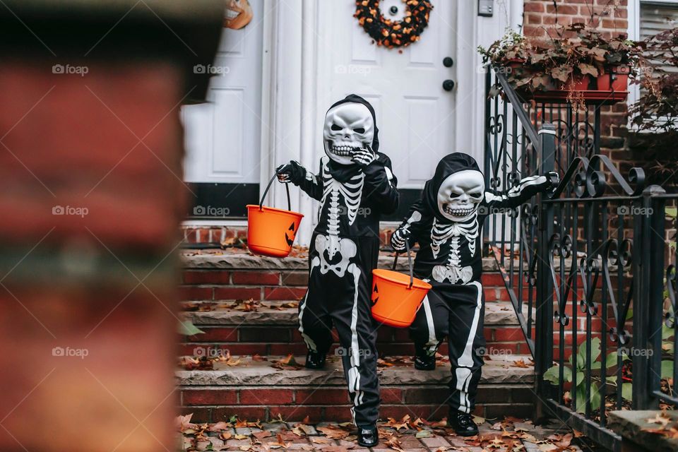 
Anonymous kids in Halloween costumes trick or treating , Orange and black 