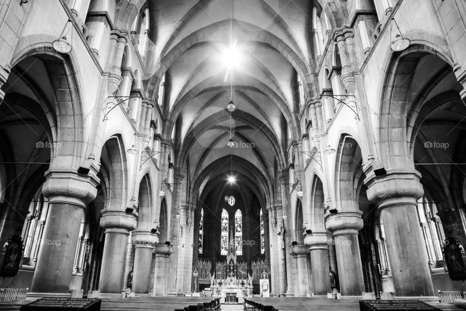 Wide angle monochrome church interior showing roof pillars and pews in beautiful symmetrical lines