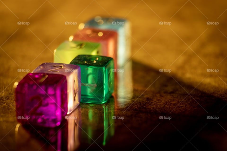 Translucent colorful dice on a shiny surface with beautiful reflections. 