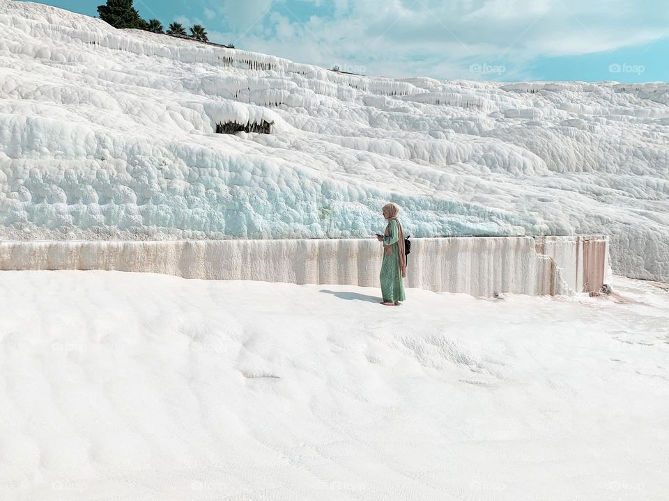 Young woman in green clothes standing on white land 