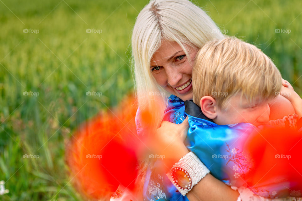 Mom with her son in a magnificent meadow. The boy embraces his mother tightly and lovingly.