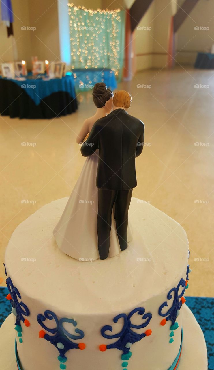 A caketopper of an embracing couple gaze out upon the reception hall awaiting the arrival of the wedding guests.